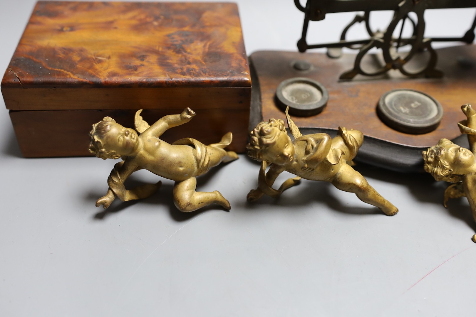 A set of three 19th century cast bronze cherubs, a set of lacquer coasters, a postal scale and a yew box